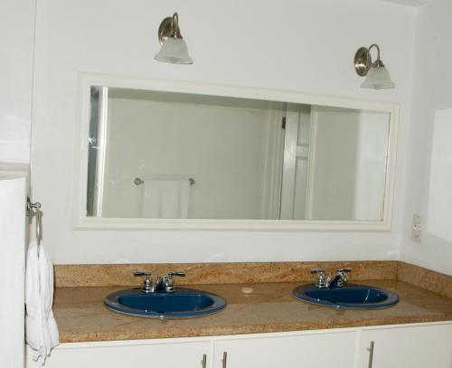 a bathroom counter with two sinks and a mirror at Castles Apartments in Castries