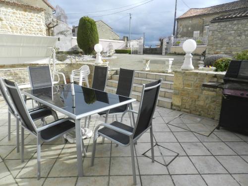 Une table à manger et des chaises sont disponibles sur la terrasse. dans l'établissement Les Quatre Saisons, à Saint-Angeau