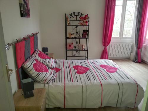 - une chambre avec un lit orné de fleurs roses dans l'établissement Gîte de Marie, à Burlats