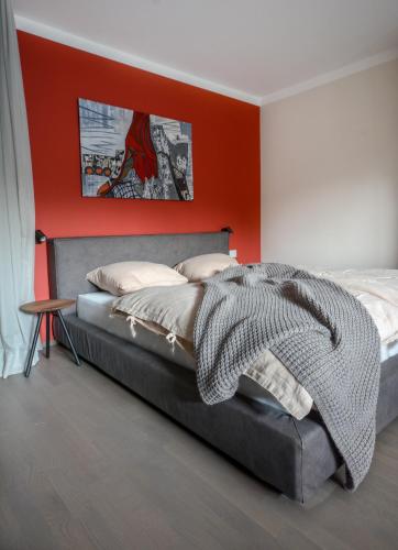 a bedroom with a bed with an orange wall at HOMEBOUND APARTMENTS Salzburg City II - contactless check-in in Salzburg