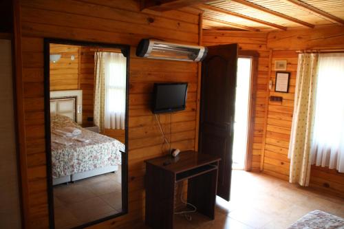 1 dormitorio con 1 cama, TV y espejo en Hotel Sunset Troia, en Dalyanköy