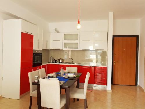 eine Küche mit roten Schränken, einem Tisch und Stühlen in der Unterkunft Appartamento Valentina in Sarandë