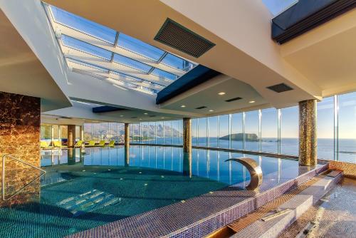 an indoor swimming pool in a house with a view of the water at Hotel Tre Canne in Budva