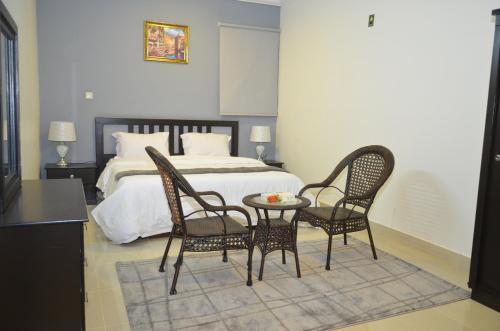 a bedroom with a bed and two chairs and a table at شقق منازل القصواء للشقق المخدومة إقتصادي in Buraydah