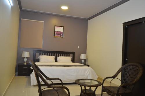 a bedroom with a bed with two chairs and a table at شقق منازل القصواء للشقق المخدومة إقتصادي in Buraydah