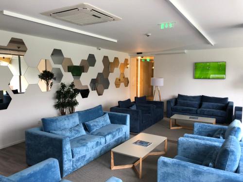 a living room with blue couches and a tv at Hotel do Parque in Viana do Castelo