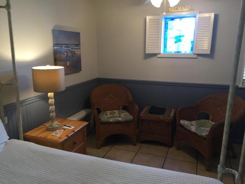 a bedroom with a bed and two chairs and a lamp at Catalina Island Seacrest Inn in Avalon