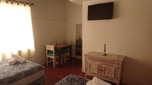 a room with two beds and a television on the wall at Villa Mimi in Otavalo