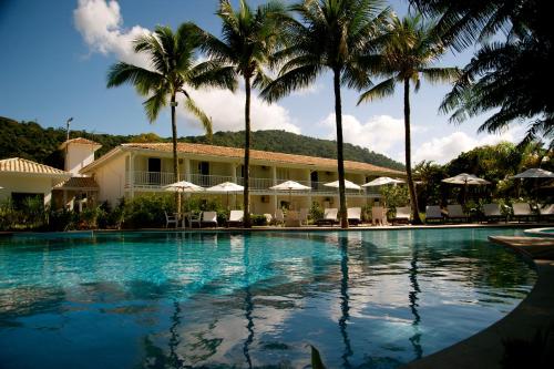 una piscina con palmeras frente a un edificio en Costa Verde Tabatinga Hotel, en Caraguatatuba