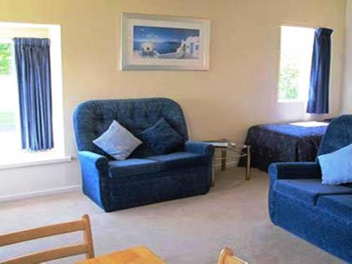 a living room with a chair and a bed at Riverview Motel in Whanganui