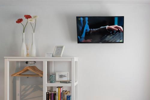 a tv hanging on a wall above a white book shelf at The Sea Beach House in Cortegaça