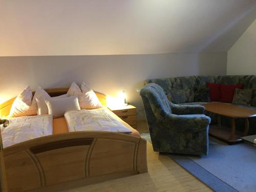 a bedroom with a bed and a couch and a chair at Ferienwohnung Mujcic in Hermagor