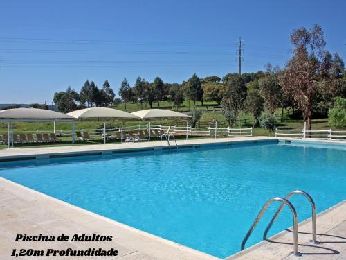 a large blue swimming pool with umbrellas at Hotel Rural da Ameira in Montemor-o-Novo