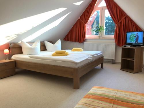 ein Schlafzimmer mit einem Bett und einem TV im Dachgeschoss in der Unterkunft Family Apartments Tom in Ostseebad Karlshagen