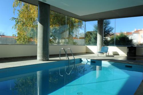 a swimming pool in a house with glass windows at Hotel Turismo De Trancoso in Trancoso