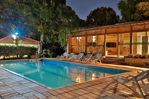 a swimming pool with chairs and a house at Solar dos Ipês in Serra do Cipo