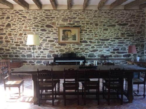 un mur en pierre avec une table et un piano dans l'établissement Magnifique corps de ferme XVII ème, à Romille