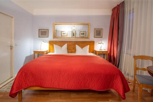 a bedroom with a red bed with a red blanket at Das Literaturhotel Berlin in Berlin