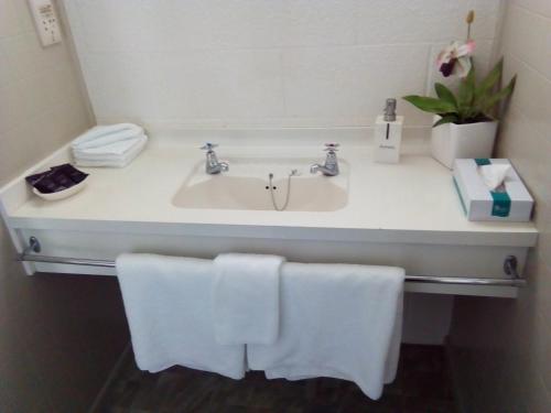a bathroom with a sink with towels on it at Redwood Lodge Motel in Levin
