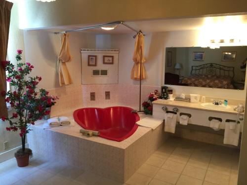 a bathroom with a red tub and a sink at Don Q Inn in Dodgeville