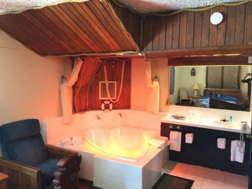 a bathroom with a tub and a chair and a sink at Don Q Inn in Dodgeville