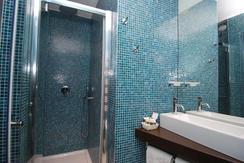 a bathroom with a sink and a shower with blue tiles at Hotel La Pergola in Grezzana
