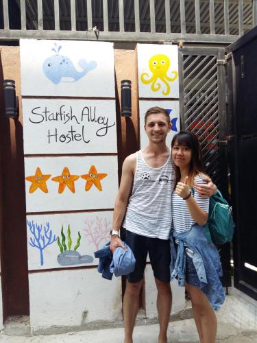 a man and a woman standing in front of a sign at Starfish Alley Hostel in Da Nang