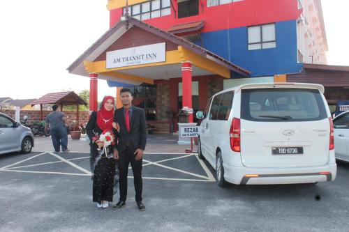 a man and a woman standing next to a white van at AM Transit Inn Kuala Terengganu in Kuala Terengganu