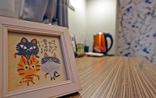 a picture of two cats in a picture frame on a table at Mori Inn in Beipu