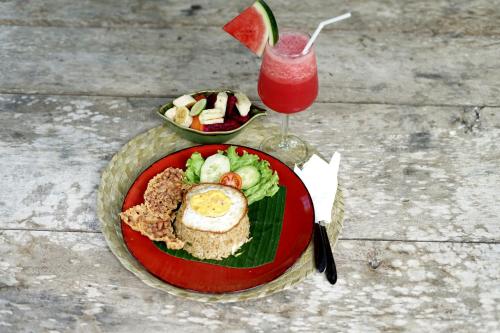 une assiette de nourriture et une boisson sur une table dans l'établissement Imagine Bali, à Ubud