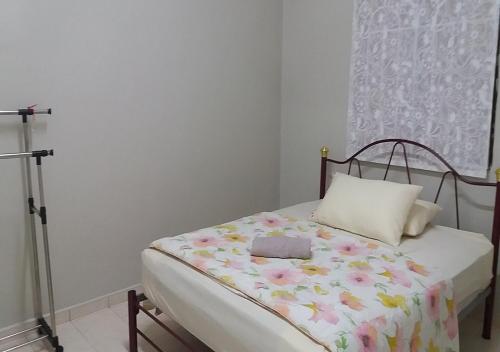een kleine slaapkamer met een bed met bloemen erop bij Taman Tanjung Minyak Homestay in Melaka
