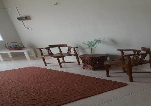 een woonkamer met houten stoelen en een tafel bij Taman Tanjung Minyak Homestay in Melaka