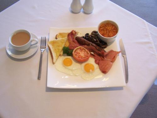 a white plate topped with breakfast foods and a cup of coffee at Hospitality Kalgoorlie, SureStay by Best Western in Kalgoorlie