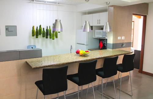 a kitchen with a counter with chairs and a refrigerator at Apartamentos Reforma in Guatemala