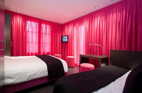 a bedroom with red curtains and a bed and a desk at Hôtel Montmorency & Spa in Carcassonne