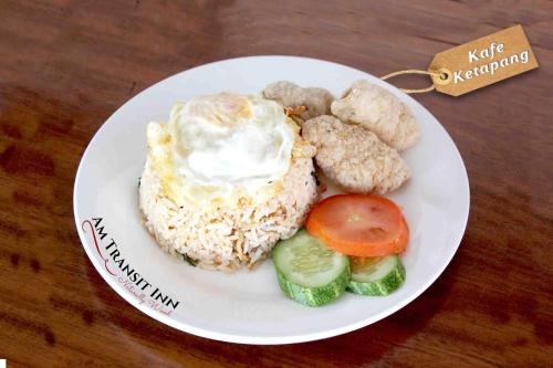 a plate of food with a fried egg and vegetables at AM Transit Inn Kuala Terengganu in Kuala Terengganu