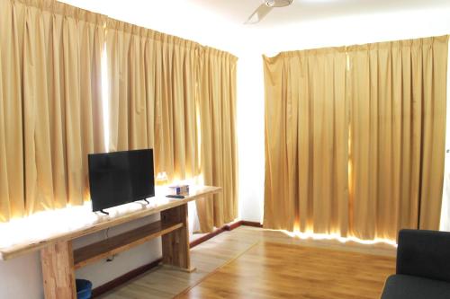 a living room with curtains and a television on a desk at AM Transit Inn Kuala Terengganu in Kuala Terengganu