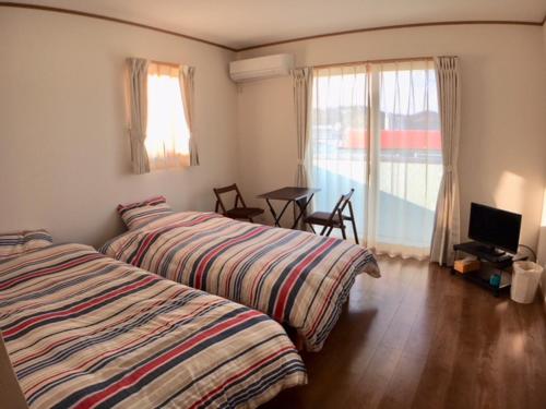 a bedroom with two beds and a table and a window at Sea Side Hostel Light House in Onomichi