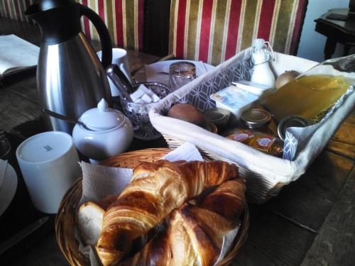 einen Tisch mit einem Korb mit Brot und Gebäck in der Unterkunft Chambres d'Hôtes L'Hirondelle du Lac in Peyrat-le-Château