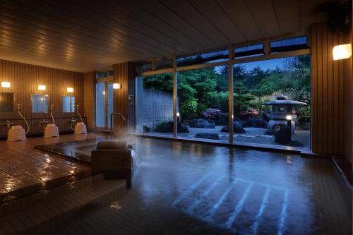 a room with a swimming pool with a view of a garden at Annex Fujiya Ryokan in Kaminoyama