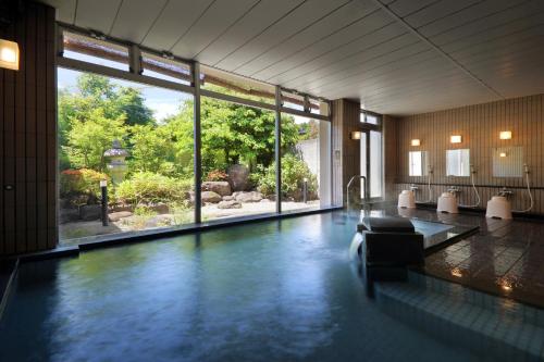 a swimming pool in a building with a large window at Annex Fujiya Ryokan in Kaminoyama