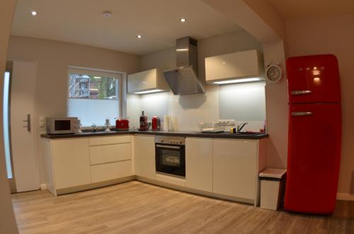 a kitchen with white cabinets and a red refrigerator at Ferienhaus Rosi in Kiel