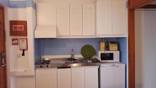 タヴィラにあるBeach Apartment in Cabanas de Taviraの白いキャビネット、シンク、電子レンジ付きのキッチンが備わります。