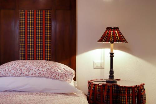 a lamp sitting on a table next to a bed at Fattoria Poggerino in Radda in Chianti