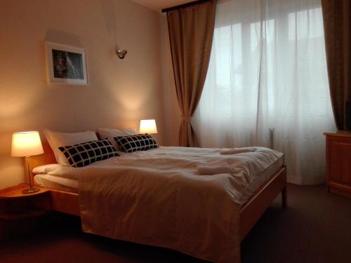 a bedroom with a bed with two lamps and a window at Horizont Dobrinishte in Dobrinishte