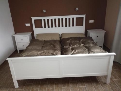 a white bed in a room with two night stands at Comfortable house for relax and sports in Hněvkovice