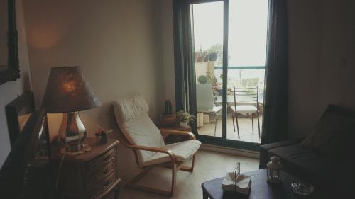 a living room with a white chair and a window at On The Lake in Tiberias