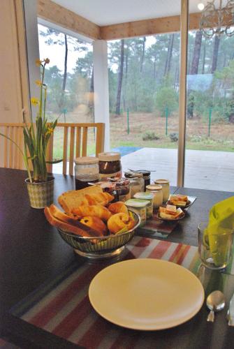 a table with a bowl of bread and other food at Villa Donosti Chambres d'Hôtes in Lanton