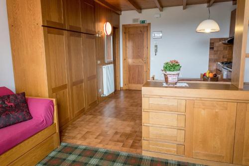 uma cozinha com um sofá rosa num quarto em Residence Des Alpes em Asiago