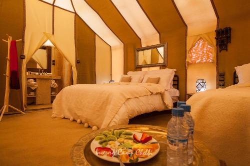 a room with two beds and a tray of food at Luxury Camp Chebbi in Merzouga